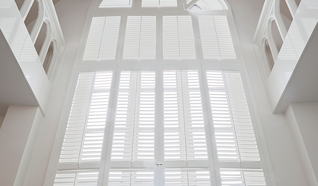 Witte shutters voor een hoog raam met een ronde vorm